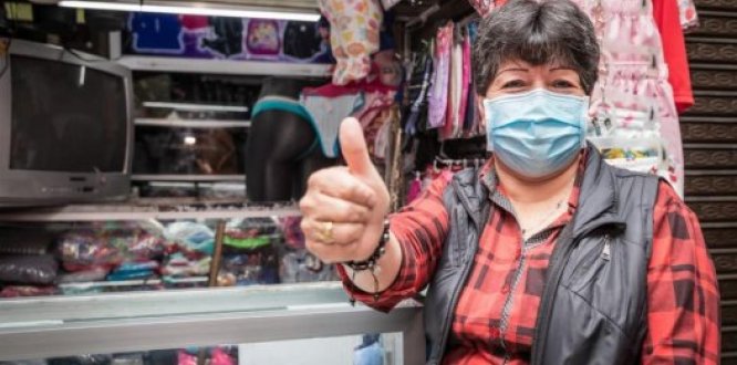 Beneficiara de Impulso Local en su negocio de ropa levantando el dedo gordo de la mano derecha